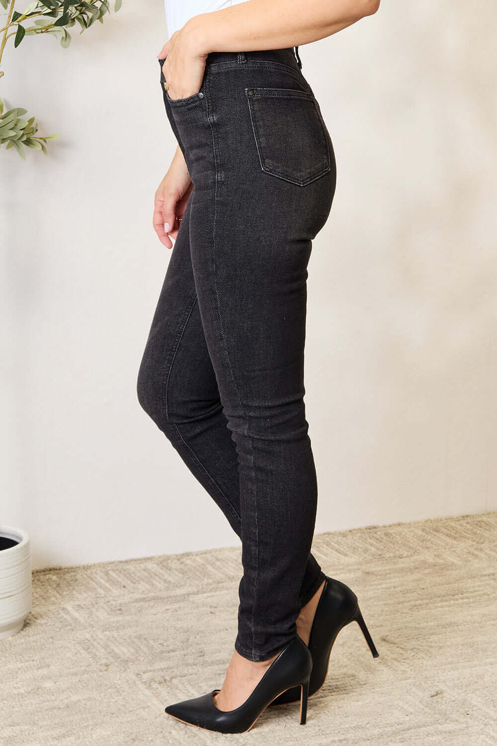 Model wearing Judy Blue high waist tummy control denim jeans in black with slightly stretchy material and sleek pocketed design.