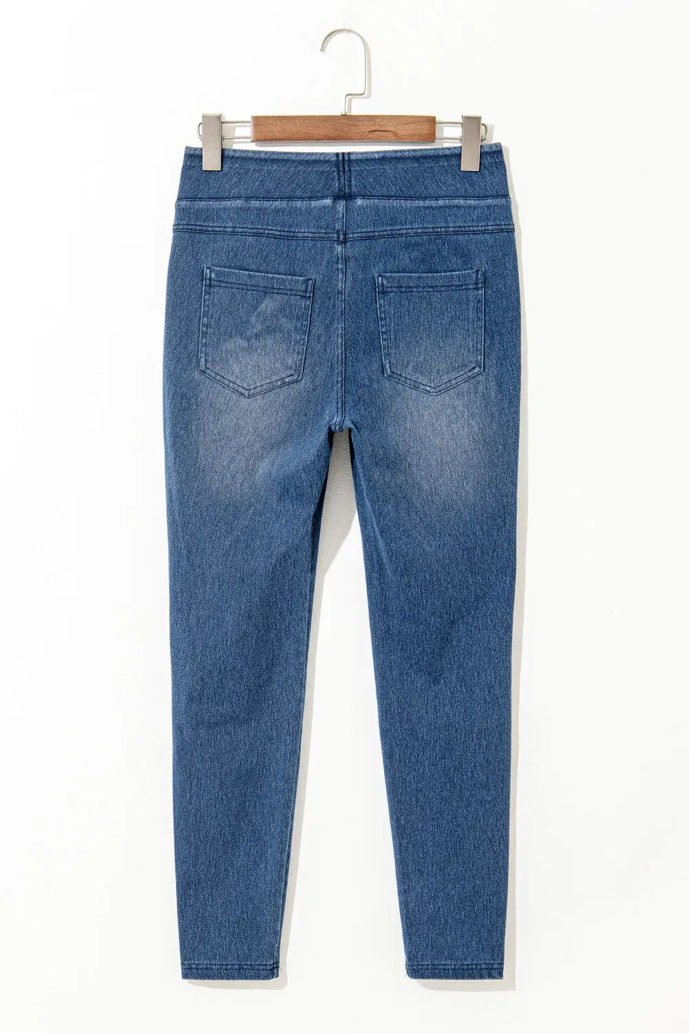 High waist skinny jeans with back pockets hanging on a wooden hanger