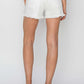 Woman wearing white button fly frayed hem denim shorts from Risen Jeans, showcasing stylish back view with chic frayed detailing.