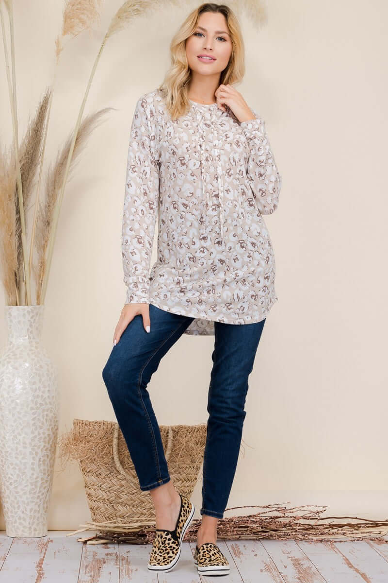 Woman in leopard print long sleeve blouse and jeans, posing stylishly against a neutral backdrop with natural decor.