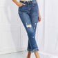 Woman wearing Undone Chic Straight Leg Jeans with distressed details and raw hem, paired with a crop top. Casual Risen Jeans style.