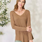 Woman wearing a luxurious rayon long sleeve V-neck top in brown, showcasing a flattering neckline and versatile design.