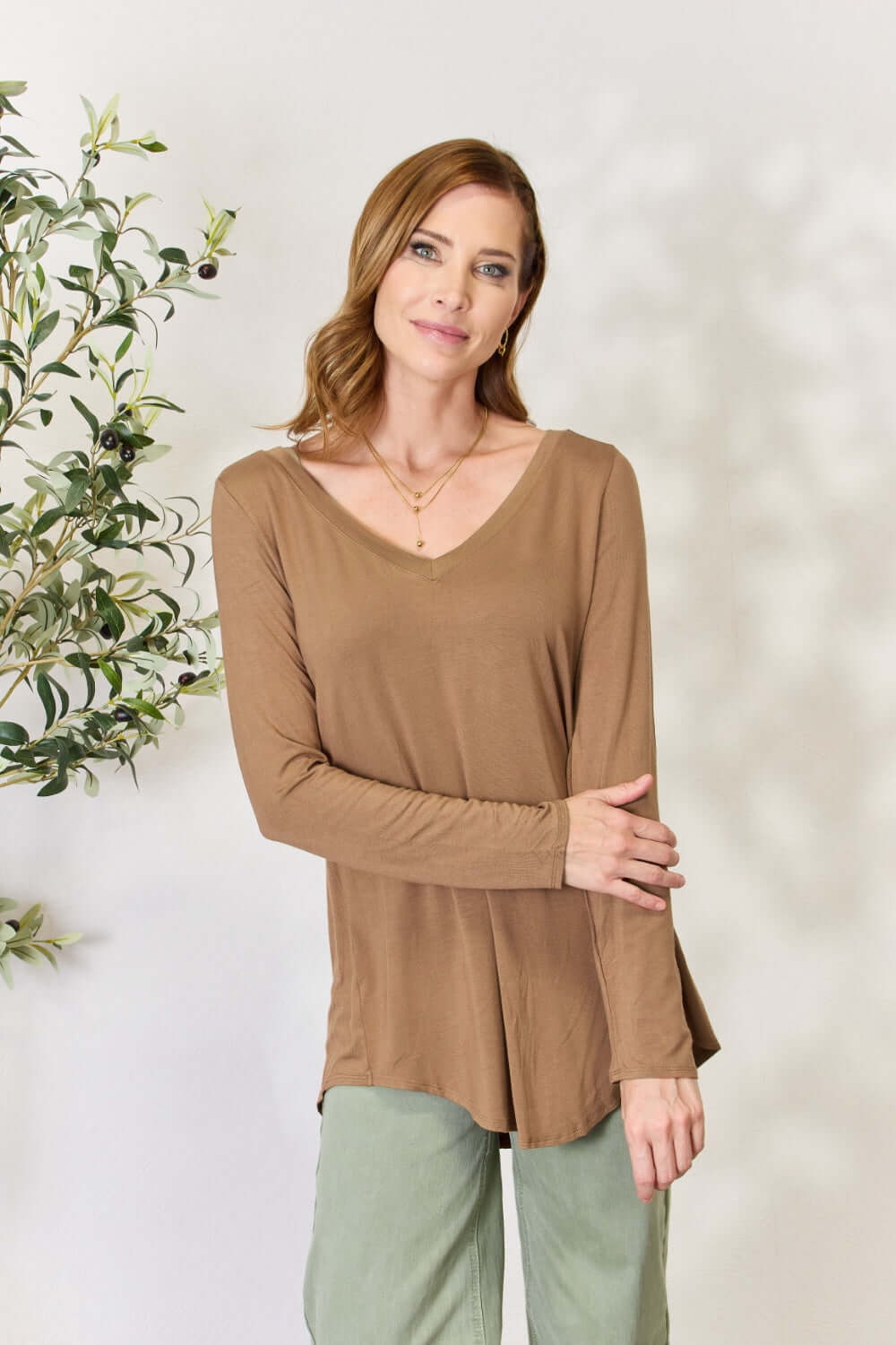 Woman wearing a luxurious rayon long sleeve V-neck top in brown, showcasing a flattering neckline and versatile design.