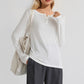 Woman wearing Basic Bae Notched Long Sleeve T-Shirt with a notched neckline, styled with dark pants and a white bag.