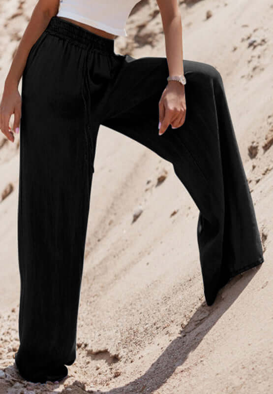 Stylish model showcasing black Bella Road Drawstring Wide Leg Jeans on sandy terrain, combining comfort and fashion effortlessly.