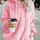 Model wearing a pink Bella Road quarter-zip drawstring teddy hoodie, holding a coffee cup on a city street.