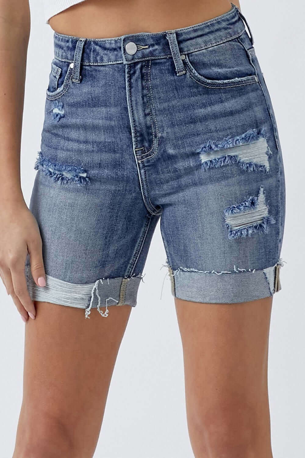 Distressed rolled denim shorts with practical pockets, showcasing ripped design and rolled cuffs by Risen Jeans. Perfect for summer fashion.