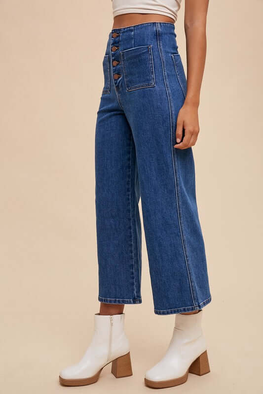 Side view of Annie Wear high waist jeans featuring button fly closure, paired with a stylish crop top and chic white boots.