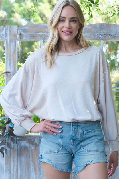 Casual style with cream pullover top and denim shorts in a garden setting.