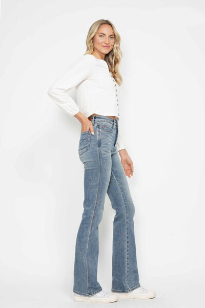 Stylish woman in Judy Blue tummy control bootcut jeans with embroidered pockets, showcasing a trendy and flattering fit.