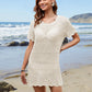 Woman on the beach wearing a Bella Road Swim Openwork Round Neck Short Sleeve Cover-Up, showcasing a stylish summer look.