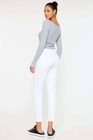 Woman wearing mid rise ankle skinny jeans in white, paired with a gray top and black sneakers.