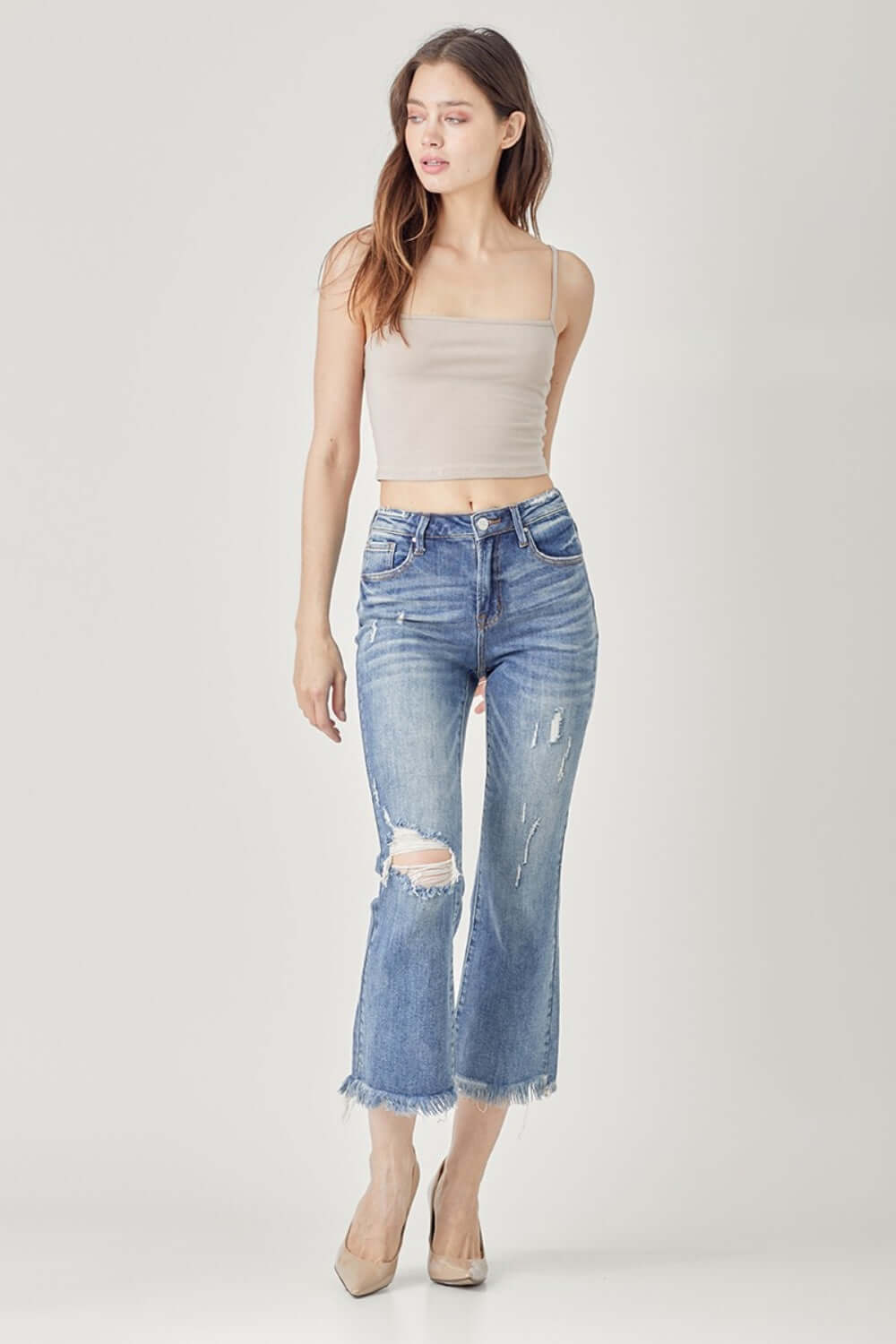 Fashion model wearing high waist distressed cropped bootcut Risen Jeans, showcasing contemporary style with a flattering, edgy look.