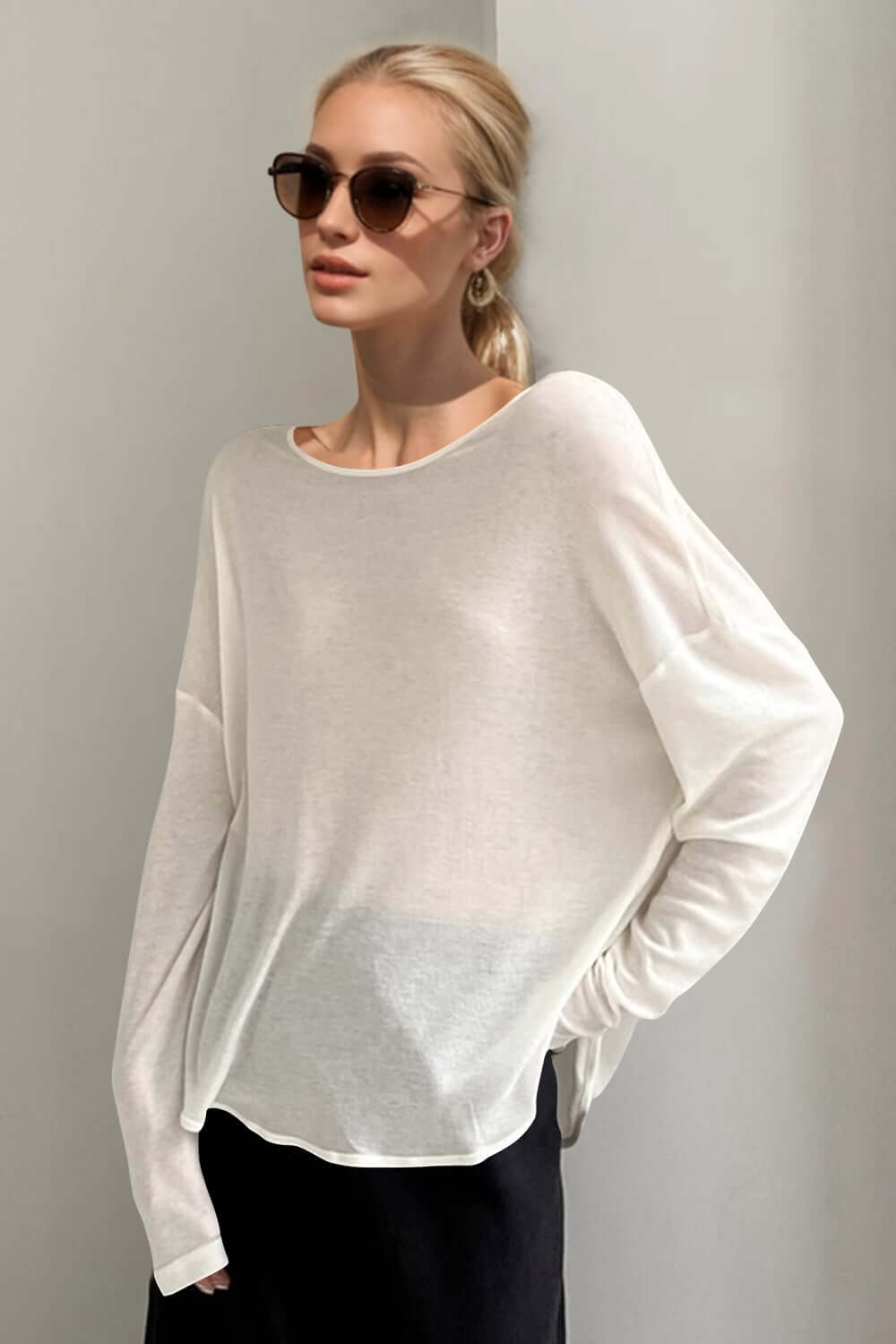 Woman wearing a stylish white high-low long sleeve t-shirt with sunglasses, embodying basic bae vibes in a trendy, casual look.