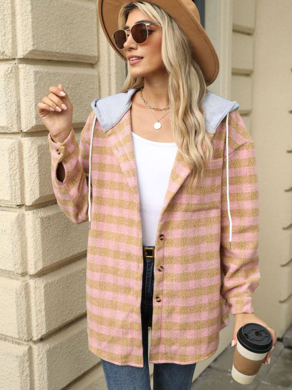 Woman wearing Bella Road Plaid Long Sleeve Hooded Jacket with drawstring and holding coffee cup, paired with hat, sunglasses, and jeans.