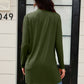 Woman wearing an open front long sleeve cardigan with pockets in green, standing outside a door in casual jeans.