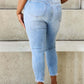 Woman wearing Judy Blue Button Fly Raw Hem Jeans, showcasing back pockets and raw hem on light blue denim.