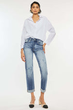 Woman wearing high rise cuffed straight jeans with white blouse and heels.