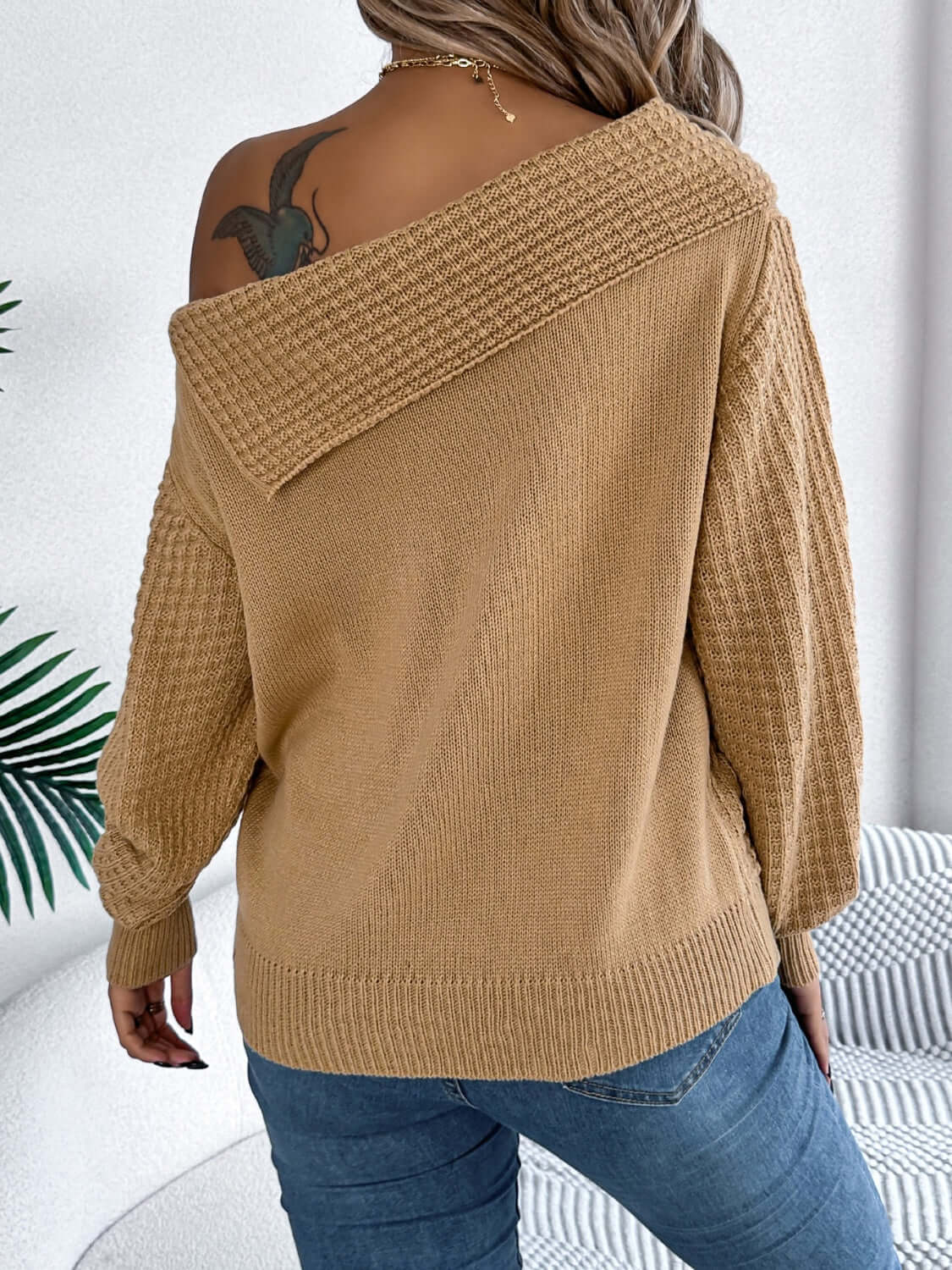 Woman wearing Bella Road Cable-Knit One Shoulder Long Sleeve Sweater in beige, showing back view with stylish off-shoulder design.