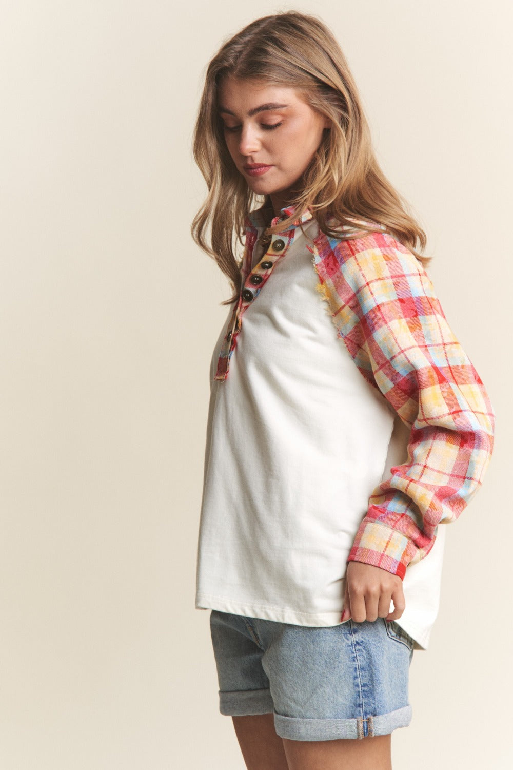 Stylish woman wearing J.NNA Plaid Contrast Button Down Henley Top with colorful plaid sleeves and denim shorts, casual chic look.