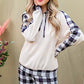 Woman smiling in a cozy drawstring hooded top and plaid pants lounge set, showcasing relaxed chic style.