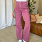 Woman wearing RFM Full Size High Rise Garment Dye Wide Leg Jeans in rich pink color with a relaxed fit, styled with white sneakers.