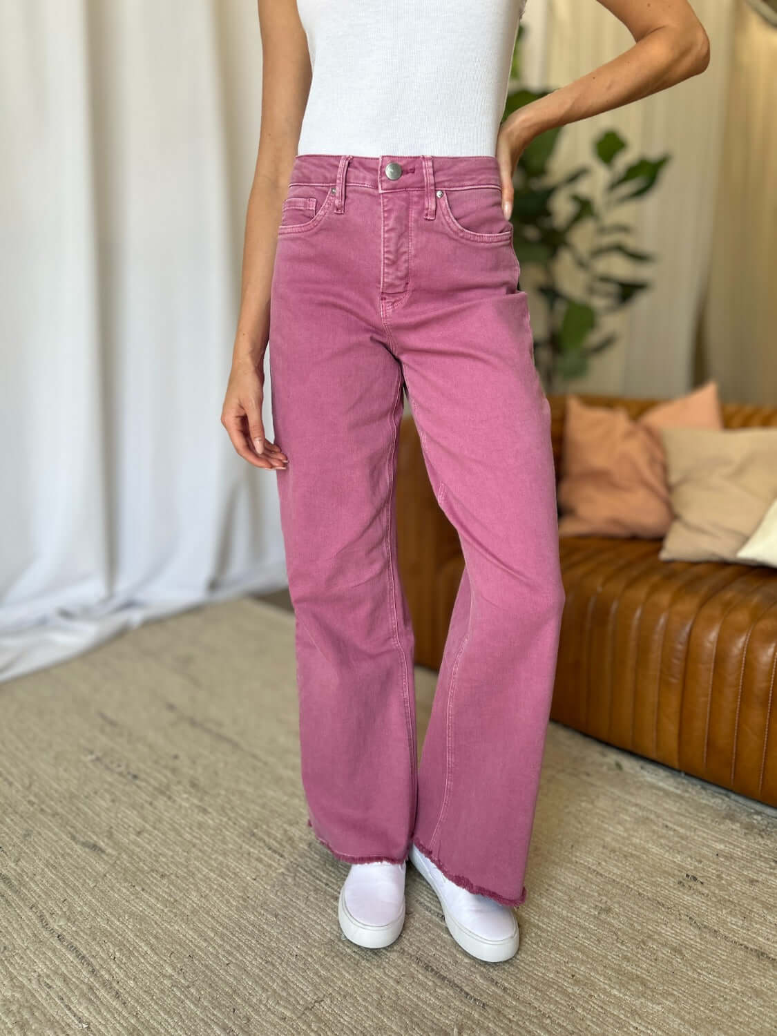 Woman wearing RFM Full Size High Rise Garment Dye Wide Leg Jeans in rich pink color with a relaxed fit, styled with white sneakers.