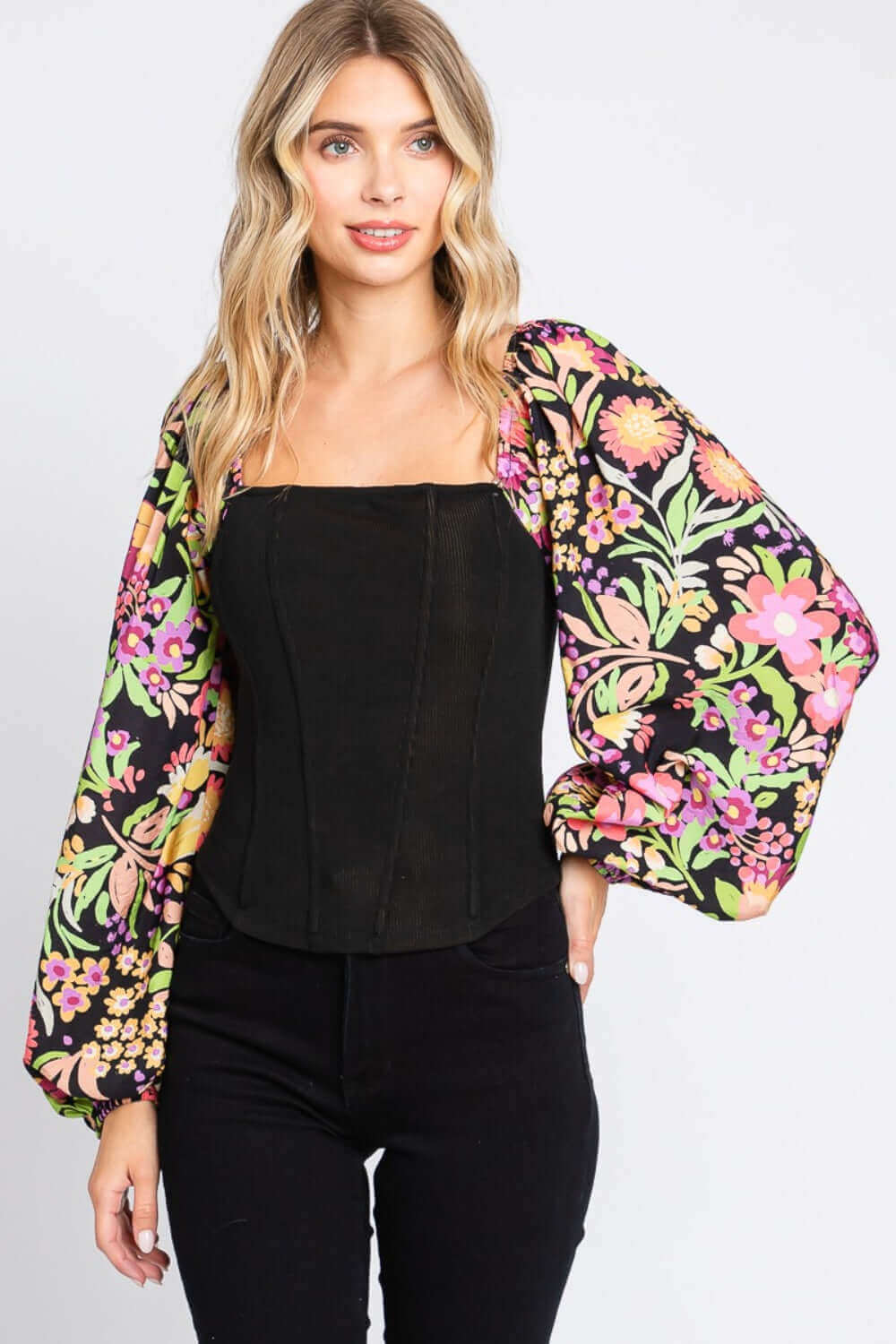 Woman wearing a chic floral balloon sleeve blouse with a black fitted bodice, showcasing a stylish and feminine fashion-forward look.