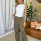 Woman modeling high-rise garment dye wide-leg jeans with a white top in a stylish, casual indoor setting