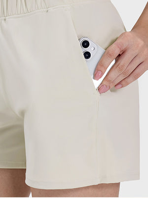 Close-up of Millennia Elastic Waist Active Shorts with a smartphone in the pocket, showcasing comfort and functionality.