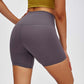 Woman wearing Millennia high waist training shorts in gray, showcasing the stretchy material and fitted design.