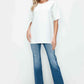 Woman in a white oversized shirt and distressed high rise jeans with pockets, showcasing modern vintage style.