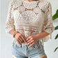 Openwork round neck cover-up in cream, styled with distressed denim shorts for a chic beach look.