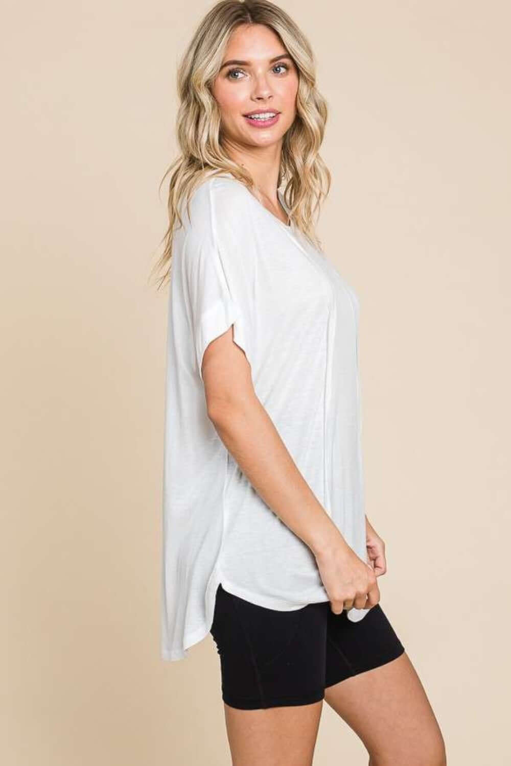 Woman wearing a white round neck short sleeve t-shirt with black shorts, showcasing a casual and comfortable look.