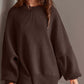 Woman wearing Double Take Side Slit Round Neck Long Sleeve Sweater in dark brown with playful side slit design.