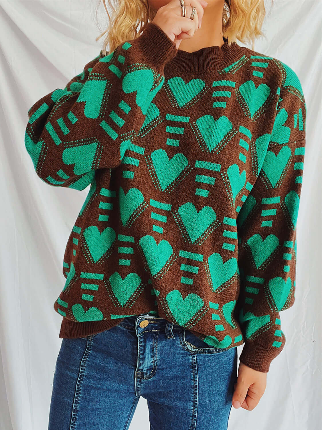 Woman wearing Bella Road Heart Contrast Long Sleeve Dropped Shoulder Sweater with green hearts and jeans.