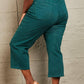 Woman wearing Hailey full size tummy control high waisted cropped wide leg teal Judy Blue jeans with heels