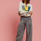 Model wearing a cozy sweatshirt with colorful graphic and flowy printed pants against a pink background.