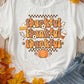 Bella Road THANKFUL Round Neck Short Sleeve T-Shirt with autumn-themed design, surrounded by fall leaves and denim shorts on a wooden background