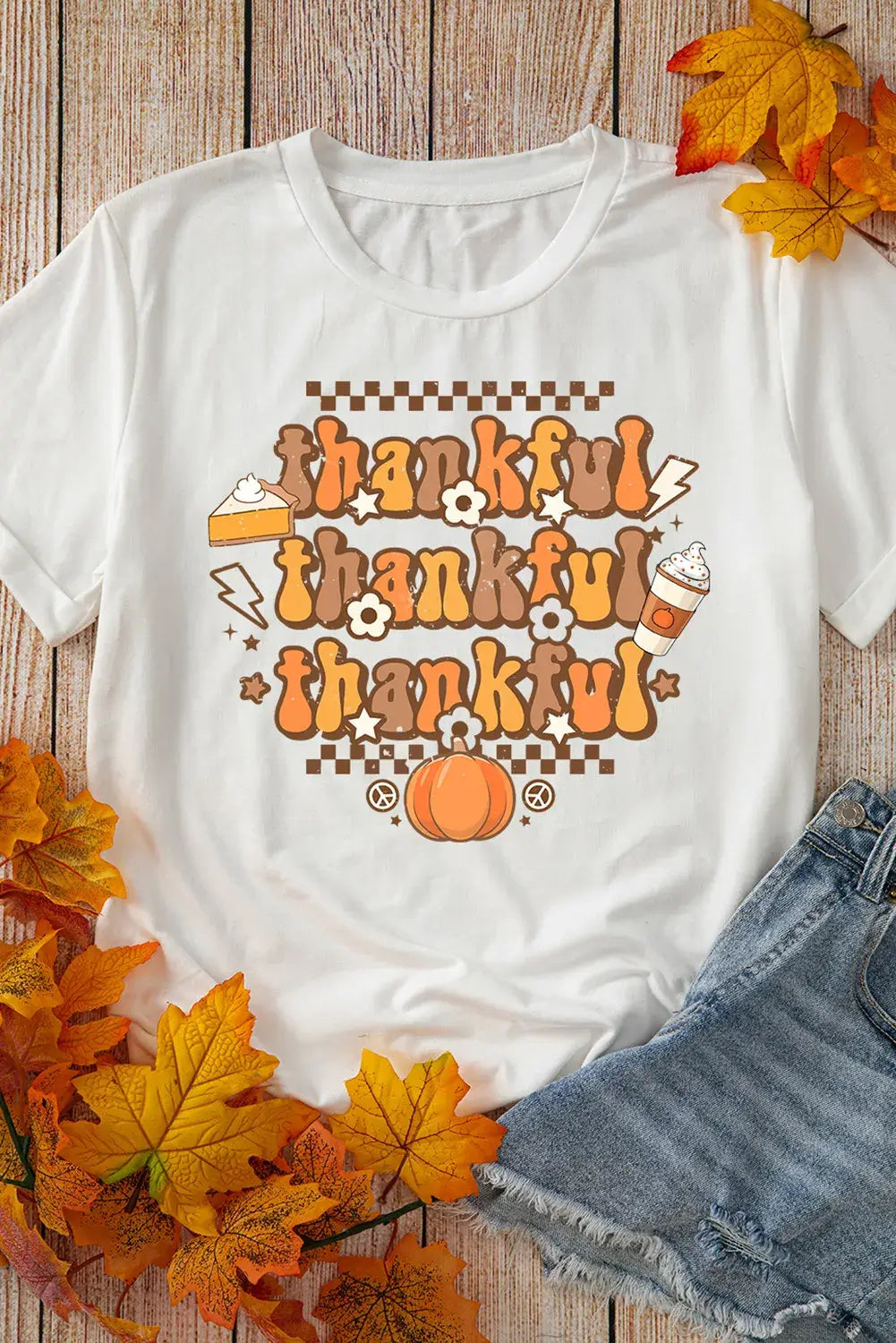 Bella Road THANKFUL Round Neck Short Sleeve T-Shirt with autumn-themed design, surrounded by fall leaves and denim shorts on a wooden background