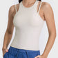 Stylish woman in a beige racerback active tank top, showcasing a modern cutout design and comfortable fit.