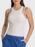 Stylish woman in a beige racerback active tank top, showcasing a modern cutout design and comfortable fit.