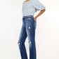 Woman modeling Kancan high-rise distressed slim straight jeans with a trendy released hem and classic 4-pocket style.