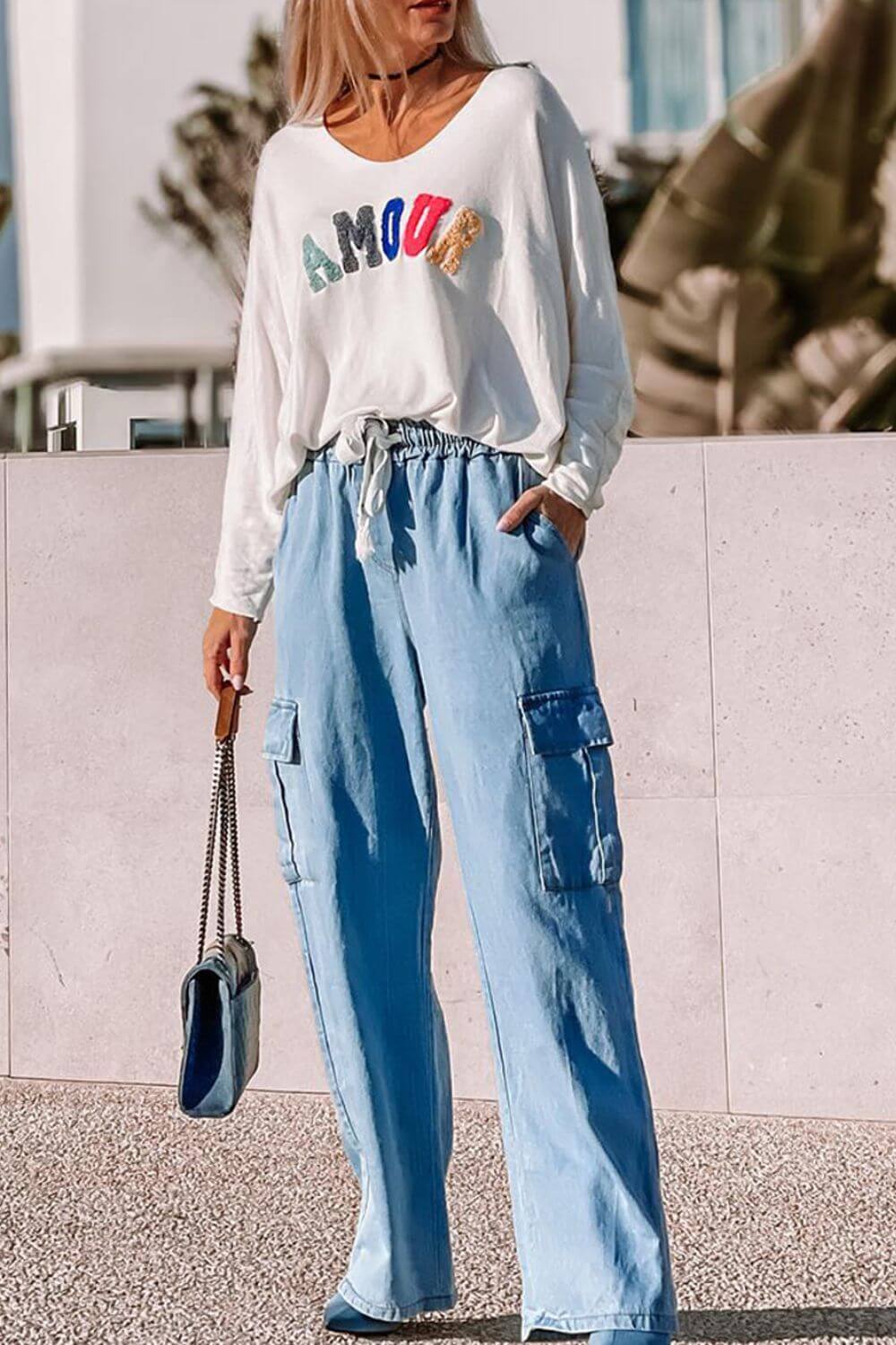 Woman wearing Bella Road light wash drawstring cargo pocket wide leg jeans with a stylish "AMOUR" graphic top.