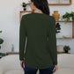 Woman wearing FAM-FAM round neck long sleeve t-shirt in army green, showcasing stylish back view in a cozy room setting.