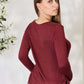 Woman wearing a drawstring round neck long sleeve top in burgundy, back view.