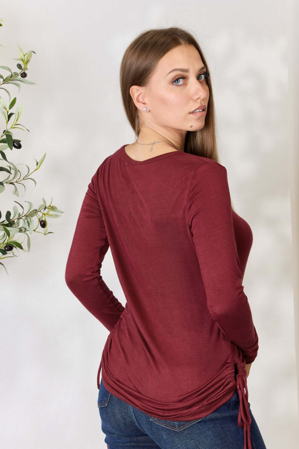 Woman wearing a drawstring round neck long sleeve top in burgundy, back view.