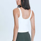 Back view of a model wearing a white Millennia V Neck Active Tank paired with green leggings, showcasing a stylish athleisure look.