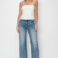 Woman wearing high waist distressed wide leg Risen Jeans and white strapless top, showcasing a chic and trendy denim look.