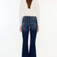 Woman wearing Kancan mid-rise button fly flare jeans in medium wash, showcasing trendy silhouette and comfort.